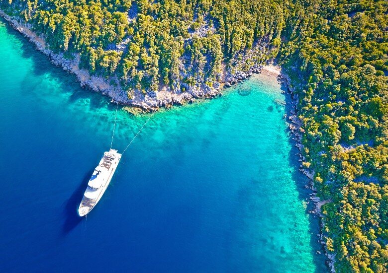 Anchored yacht in beautiful turquoise water off an island with trees