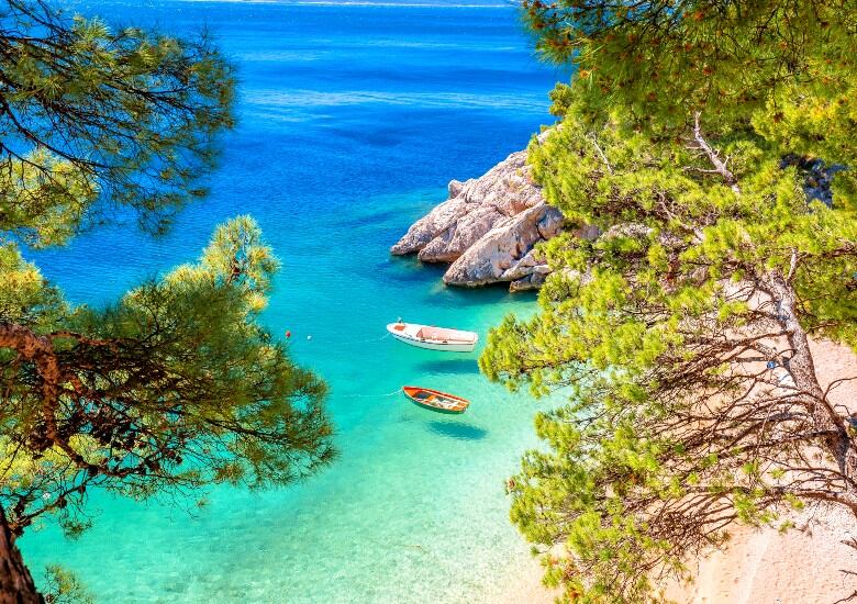 Brela Beach in Croatia with crystal-clear turquoise water with boats floating on it