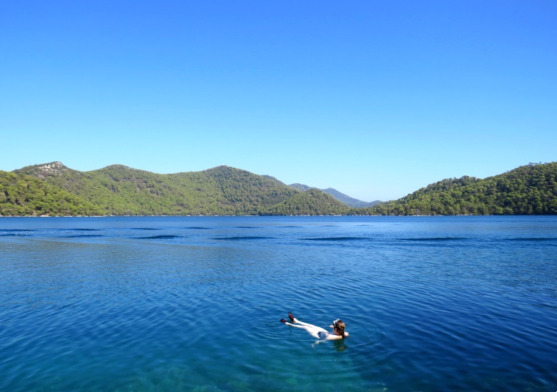 Woman floating in blue saltwater lake in Mljet National Park